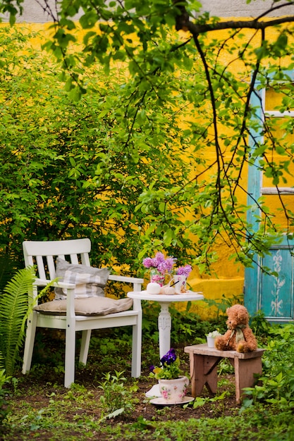 Silla de madera blanca mesa con un ramo de lilas en el jardín de primavera.