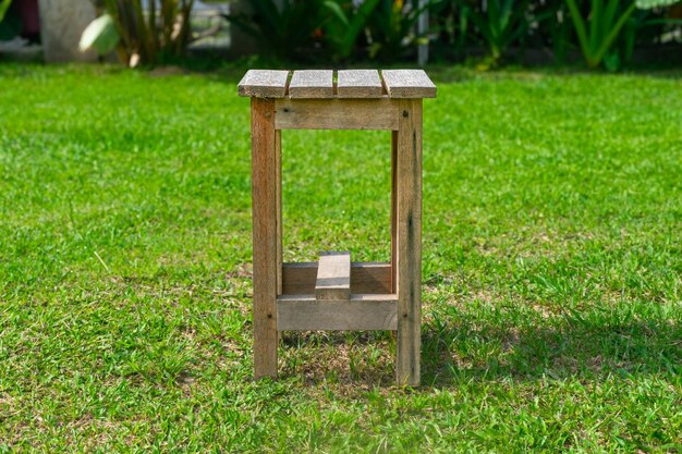 Una silla de madera está colocada en el medio de la hierba del jardín