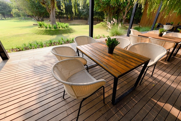 Silla de madera con mesa y flora verde en el patio.