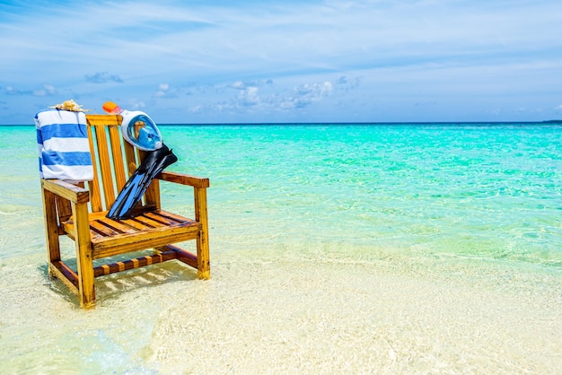 Una silla de madera en el Océano Índico con aletas de concha de toalla y máscara subacuática