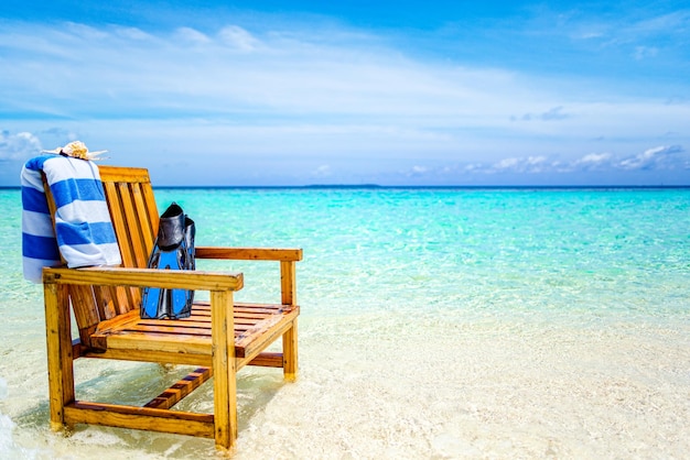 Una silla de madera de pie en el Océano Índico con una toalla y aletas