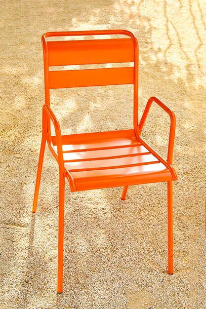 Una silla de metal naranja en la arena.