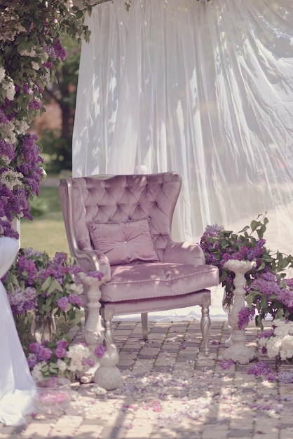 Una silla morada está en un patio con flores moradas.