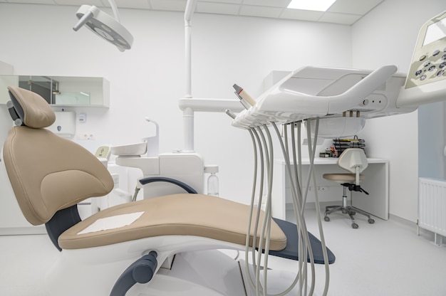 Silla de paciente en el interior de la sala médica de odontología moderna blanca con equipo especial