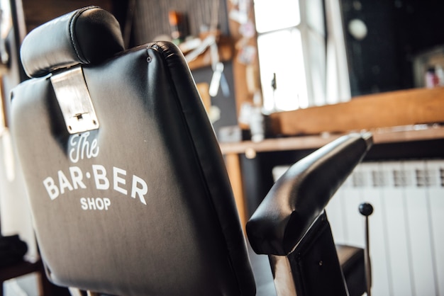 Foto silla de peluquería barberman negro contra el espejo