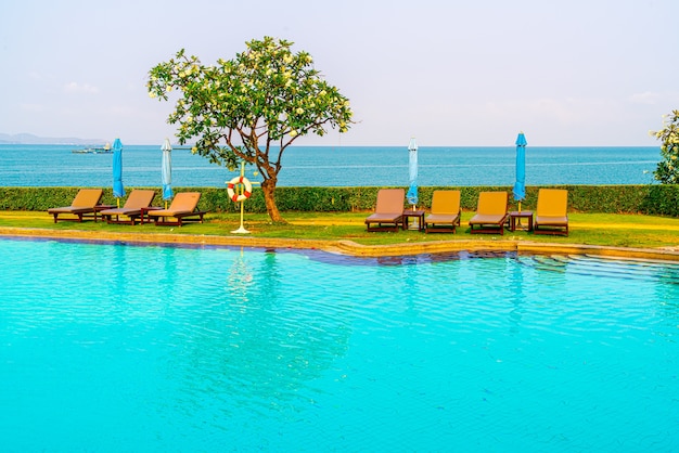 silla de piscina o cama de piscina y sombrilla alrededor de la piscina con mar. Vacaciones y concepto de vacaciones