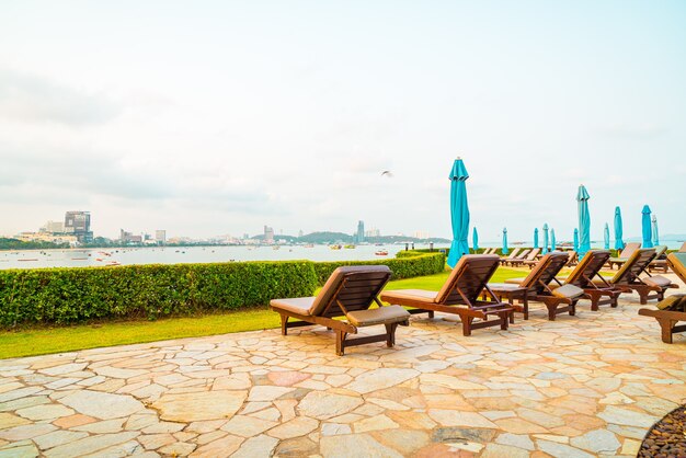 Silla de piscina o piscina de cama y sombrilla alrededor de la piscina con playa de mar en Pattaya en Tailandia