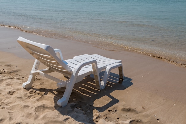 Silla de playa en la costa soleada en el fondo de la playa