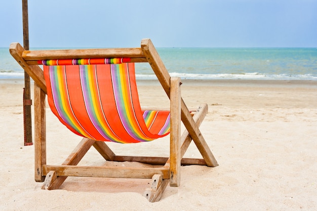 Una silla de playa de madera vacía en la playa.