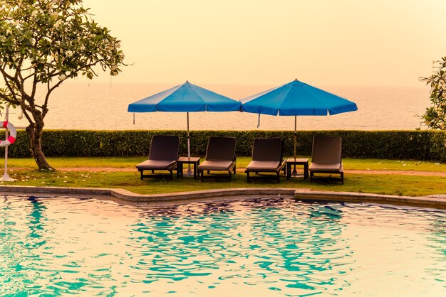 silla de playa o cama de piscina con sombrilla alrededor de la piscina con puesta de sol y mar