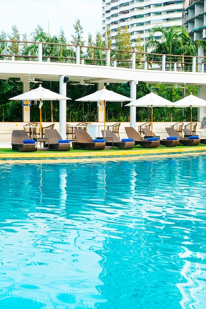 Silla de playa vacía con sombrilla alrededor de la piscina