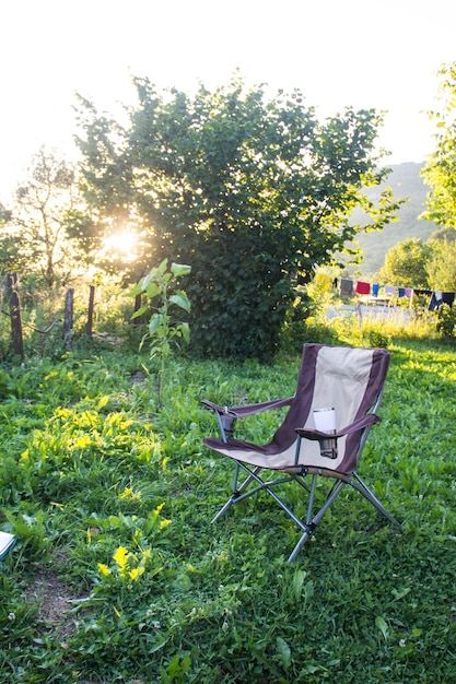 Una silla plegable vacía para acampar al aire libre en el fondo de la naturaleza al atardecer