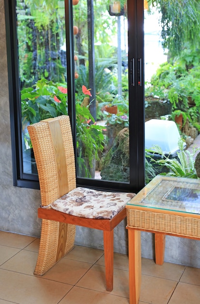 Silla de ratán y mesita en café natural cerca de la planta del jardín.