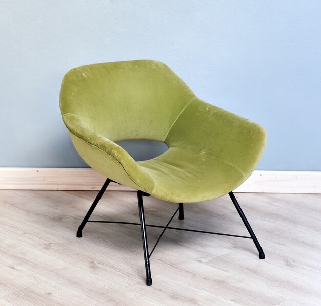 Silla retro de terciopelo verde en la habitación con paredes azules