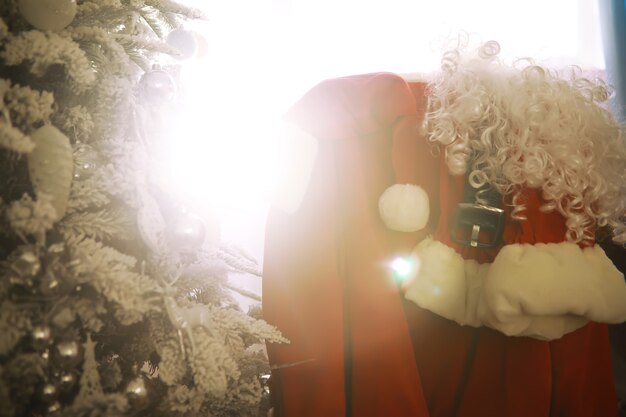Silla con ropa de Santa Claus. Traje de Papá Noel colgado en la sala blanca