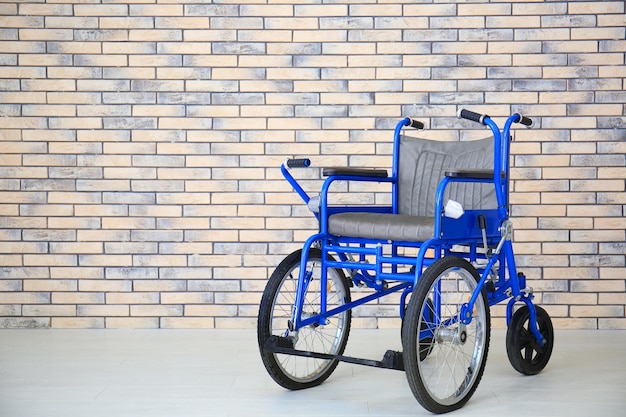 Silla de ruedas azul cerca de la pared de ladrillo en el interior