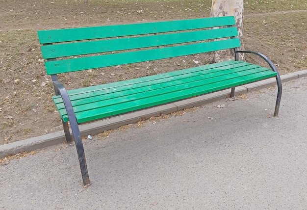 Una silla verde en el parque en la acera.