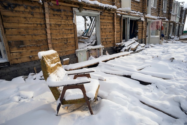 Silla vieja cubierta de nieve en una casa en ruinas.