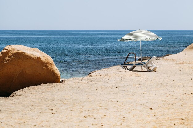 Foto sillas de cubierta bajo sombrilla en la playa contra un cielo despejado