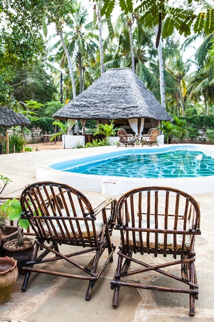 Sillas elegantes de madera cerca de una piscina dentro de un jardín de Kenia