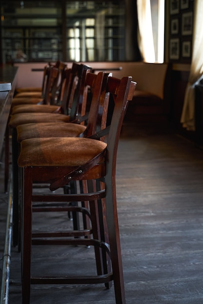 Foto sillas de madera al lado de la barra de bar en una fila. café vacío por la mañana. orientación vertical