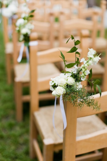 Sillas de madera con ceremonia de boda de flores.