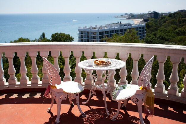 Sillas y una mesa están en la terraza con impresionantes vistas al mar