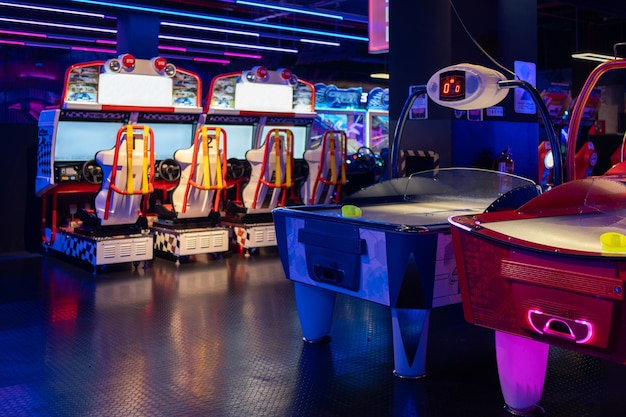 Sillas y mesa de juegos en la zona de juegos de arcade iluminada en el centro comercial