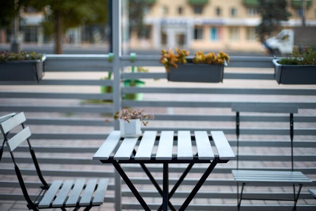 Sillas de mesa de tablones de madera blanca y valla horizontal de café en el fondo de la calle para el producto