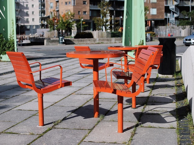 Foto sillas y mesas vacías en la acera de los edificios de la ciudad