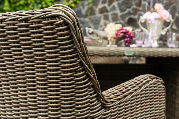 Foto sillón con asiento de mimbre y mesa de comedor muebles al aire libre contra el fondo de la pared de piedra