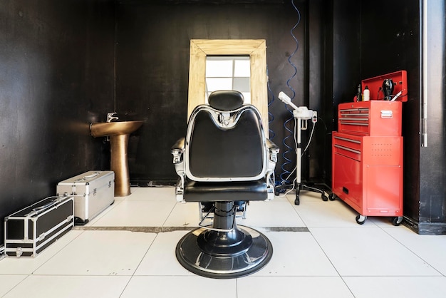 Sillón de cuero negro y metal cromado en una peluquería con decoración estilo automóvil