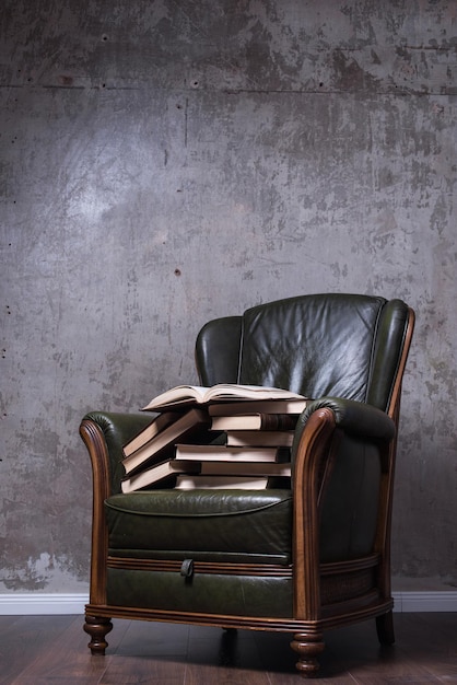 Foto sillón de cuero verde con libros frente a la pared.