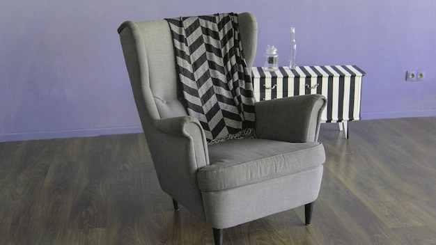 Sillón gris con tela escocesa para descansar en la sala de estar Primer plano de un cómodo sillón con tela escocesa en la habitación