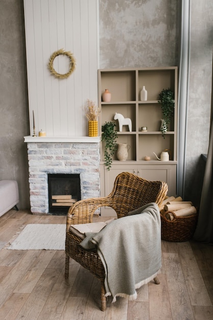 Foto sillón de mimbre con un plaid cerca de la chimenea en una casa de campo en la sala de estar de estilo escandinavo