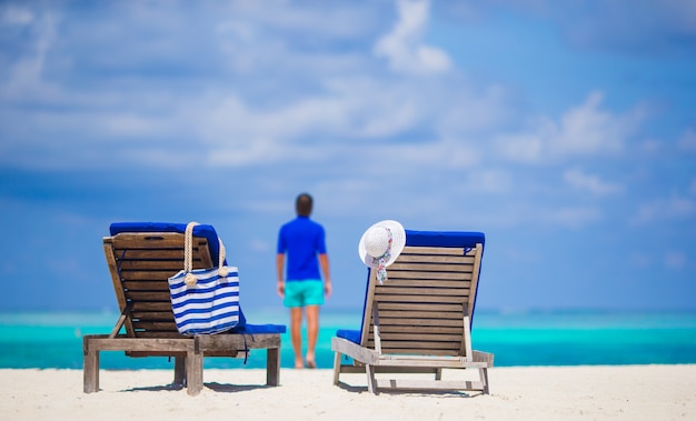 Sillones con bolsa y sombrero en playa tropical en Maldivas