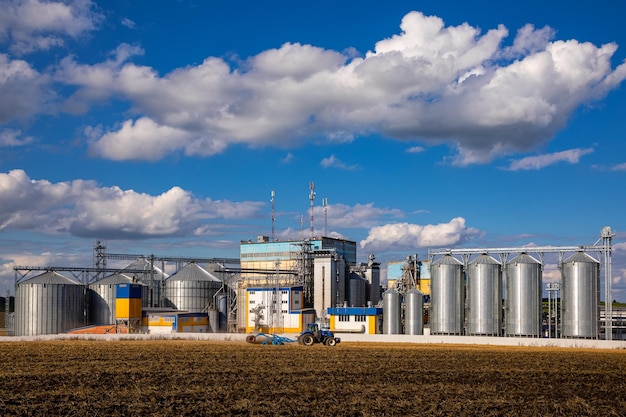 Foto silos agrícolas almacenamiento y secado de granos trigo maíz soja girasol contra el cielo azul con nubes blancas almacenamiento de la cosecha