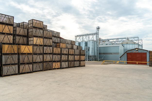 Silos de prata em fileiras de fábricas de agroindústria de caixotes de madeira e paletes para armazenamento e transporte de frutas e vegetais no armazém de produção do armazém