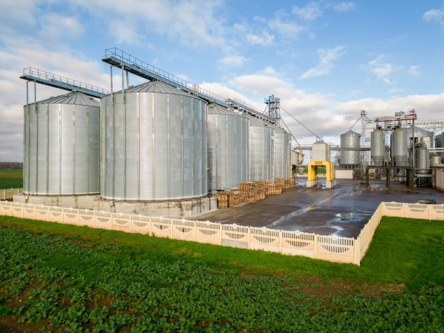 Silos de prata na planta de agroindústria para processamento de secagem, limpeza e armazenamento de produtos agrícolas, farinha, cereais e grãos Voando um drone sobre barris de ferro de grãos quadcopter photo