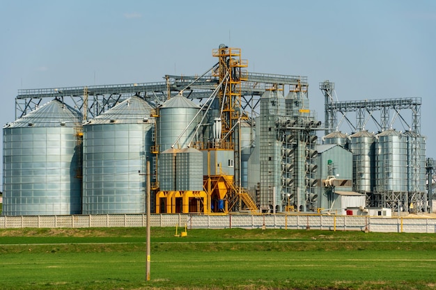 Silos de plata en la planta de fabricación agrícola para el procesamiento, secado, limpieza y almacenamiento de productos agrícolas, harina, cereales y granos Grandes barriles de hierro de grano Elevador de granero