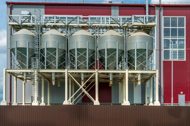 Silos de plata en la planta de fabricación agrícola para el procesamiento, secado, limpieza y almacenamiento de productos agrícolas, harina, cereales y granos Grandes barriles de hierro de grano Elevador de granero