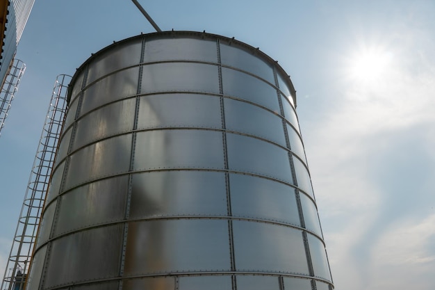 Silos de plata en la planta de fabricación agrícola para el procesamiento, secado, limpieza y almacenamiento de productos agrícolas, harina, cereales y granos Grandes barriles de hierro de grano Elevador de granero