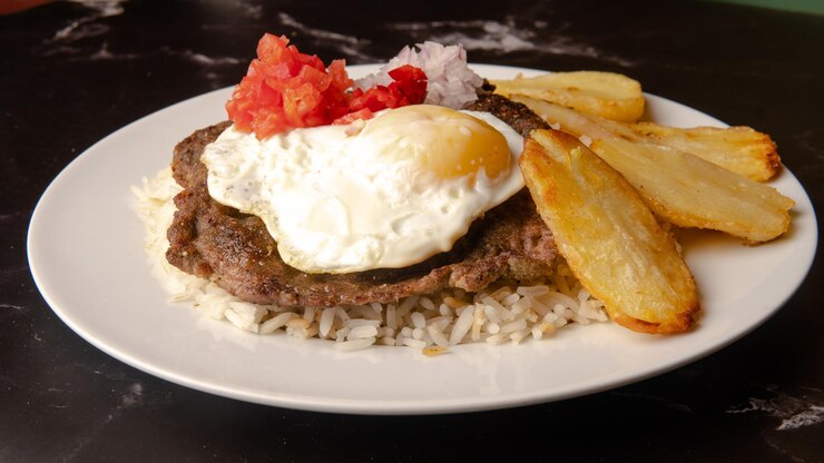Silpancho Cochabamba Primer plano de comida tradicional boliviana en el plato sobre fondo oscuro