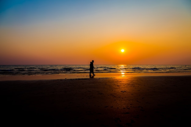 Siluate-Liebhaber und Strand vor Sonnenunterganghintergrund