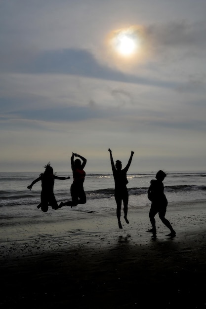 Silueta de 4 mujeres saltando en una playa al atardecer