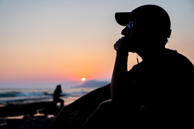 Silueta adolescente sentado en la playa en paz