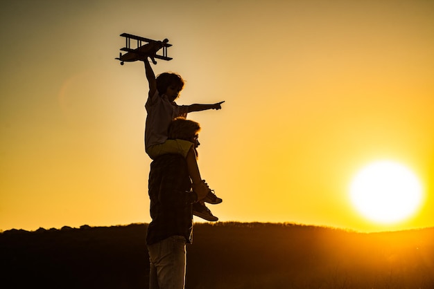 Silueta al atardecer de niño y papá jugando Kid piloto aviador y papá sueña con viajar Niño feliz