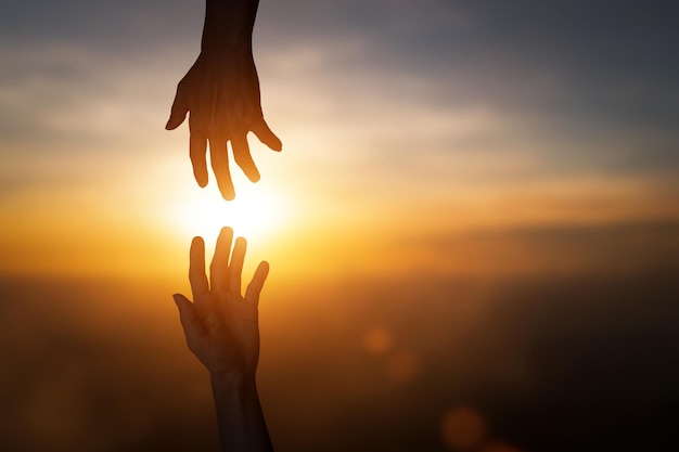 Foto silueta de alcanzar dando una mano de ayuda esperanza y apoyarse mutuamente sobre borrón puesta de sol cielo concepto de fondo del día internacional de la paz y desarrollar una amistad