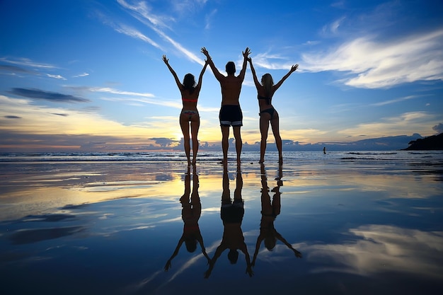 silueta de amigos puesta de sol mar verano / grupo de jóvenes amigos hombres y mujeres en verano descansan y se divierten en el mar, feliz puesta de sol en el mar