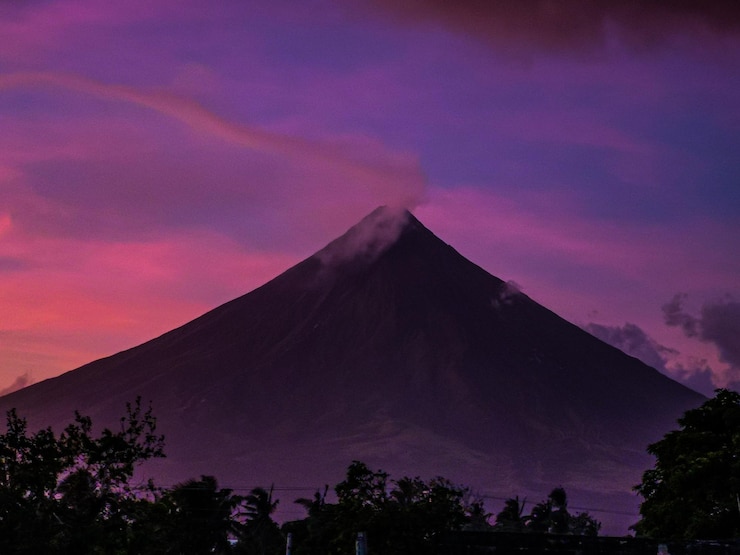 Silueta de árboles contra el cielo nublado al atardecer